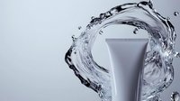 Cosmetic tube mockup with dynamic water splash effect on gray background, clean skincare packaging design for beauty and personal care products.