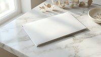 Blank white notebook open on marble surface with natural lighting and minimalist home office decor for creative writing and planning projects.