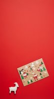 Kraft envelope decorated with festive holiday motifs including Santa, reindeer, and snowflakes on bright red background with white llama figurine for seasonal greeting card design.