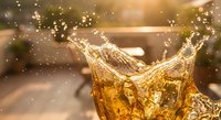 Golden whiskey splashing from glass with dramatic lighting and bokeh background creating luxury drinking atmosphere for premium spirits advertising.