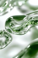 Dynamic flow of transparent liquid with green tints creating abstract wave patterns against white background, macro photography showing fluid motion.