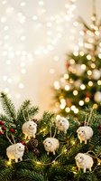 Festive holiday arrangement featuring miniature white woolly sheep ornaments nestled among evergreen branches, pinecones, and red berries with glowing bokeh lights and decorated tree in soft-focus background for seasonal celebrations.