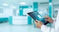 Healthcare professional using digital tablet with medical interface icons in modern hospital setting for telemedicine and patient care management.