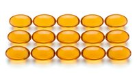Amber colored oval gel capsules arranged in neat rows on white background. Vitamin supplements, omega-3 fish oil pills for health and wellness nutrition.