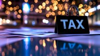 Black tax sign with golden bokeh lights background reflecting on glossy surface, financial concept for accounting and revenue season.