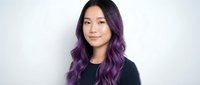 Young Asian woman with purple ombre hair smiling at camera wearing black top against white background for beauty and lifestyle content.