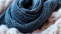 Cozy knitted blue winter scarf with chunky texture pattern in soft wool yarn, close-up macro shot showing detailed stitches and warm fabric structure.