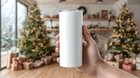 Hand holding white tumbler against festive holiday background with decorated Christmas trees, wrapped gifts, and warm interior decor.