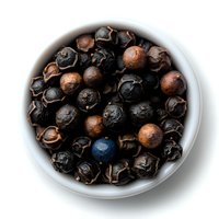 Dried juniper berries in white ceramic bowl on dark background, macro food photography showing texture and natural organic spice details for cooking.