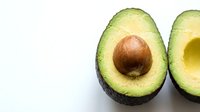 Fresh avocado halves with pit and hollow cavity displayed on white background, suitable for food photography, culinary content, healthy eating, nutrition guides, recipe blogs, and restaurant menus.
