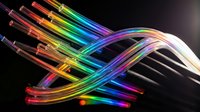 Colorful fiber optic cables with glowing rainbow light streams flowing through transparent tubes on dark background for technology and communication concepts.