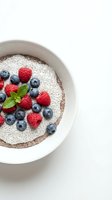 Chia seed pudding bowl with fresh raspberries, blueberries, and mint leaf garnish on white background. Healthy breakfast or dessert option.
