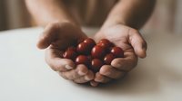 Hands gently holding fresh red cranberries in cupped palms, showcasing natural organic berries for healthy eating and seasonal harvest concepts.