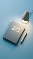 Deep work book with pen and desk lamp on blue surface, symbolizing focus, productivity, and professional development concepts.