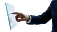 Male professional in dark business suit touching transparent glass panel with index finger against white background.