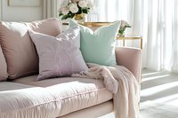 Elegant living room interior with pink velvet sofa, decorative pillows in pastel colors, floral embroidery, and soft natural lighting through sheer curtains.