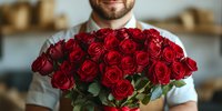 Smiling man holding large bouquet of red roses for romantic gift, valentine celebration, anniversary surprise or special occasion delivery service.