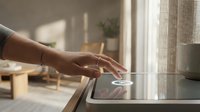 Woman hand touching modern smart home control panel on kitchen counter in contemporary interior with natural lighting for home automation technology.