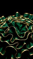 Luxurious emerald green velvet fabric with gold trim edges, featuring ruffled and wavy textures against dark background. Suitable for fashion, textile, and luxury design projects.