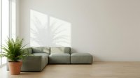Modern minimalist living room with gray modular sofa, potted fern plant, wooden floor and sunlit wall art for interior design and home decor projects.