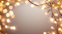 Glowing fairy lights creating magical bokeh effect on branches against soft blush background, festive holiday atmosphere for greeting cards and celebrations.