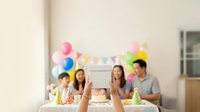 Young diverse group of friends celebrating with colorful balloons and party decorations indoors, perfect for birthday, celebration, and social gathering marketing materials.