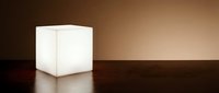 Glowing white cube lamp on dark wooden surface with warm brown background, modern minimalist lighting fixture for interior design and home decor.