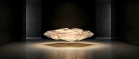 Luxury champagne diamond gemstone floating in dramatic spotlight on dark stage with elegant lighting for jewelry and precious stone concepts.