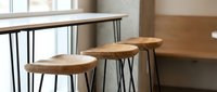 Wooden bar stools with metal hairpin legs positioned at kitchen counter, modern minimalist interior design furniture for dining and seating spaces.