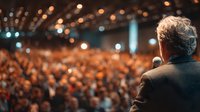 Professional speaker addressing large audience at corporate conference with stage lighting and microphone for business presentations.