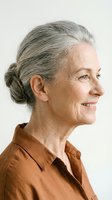 Elegant senior woman with gray hair in bun wearing brown shirt smiling in profile against neutral background for lifestyle and aging concepts.