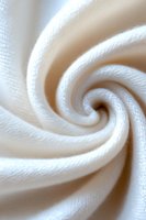 Soft white fabric swirl creating mesmerizing spiral pattern with gentle folds and textured surface, abstract macro photography showing delicate textile details.