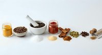 Natural spices and herbs collection with mortar pestle honey jar cinnamon sticks arranged on white marble surface for cooking seasoning culinary recipes.