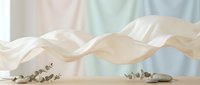 Flowing white silk fabric with elegant waves creates dreamy ethereal movement above eucalyptus branches on neutral surface for luxury branding concepts.