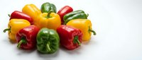 Assorted fresh bell peppers in red, yellow, and green colors arranged on white background for cooking and nutrition content.