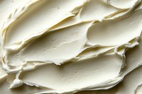 Creamy white cream cheese texture with soft swirls and waves, macro close-up showing rich, smooth dairy spread surface detail for food photography.