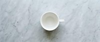 Empty white ceramic mug on marble surface, overhead view. Suitable for beverage, coffee, tea, and kitchen product mockups.