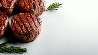Grilled beef tenderloin medallions with fresh rosemary sprigs on light background, juicy meat with seared grill marks showing medium rare doneness.