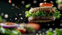 Fresh juicy burger with sesame bun and green lettuce floating in air with motion blur effect and scattered ingredients on dark background. Food photography.