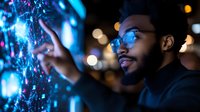 Young African American man in glasses touching futuristic holographic interface with glowing blue lights against dark background with bokeh effect. Technology concept.