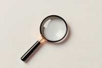 Elegant magnifying glass with black handle and metallic rim on beige background, isolated view for business and investigation concepts.