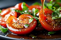 Fresh sliced tomatoes with herbs and olive oil drizzle on dark plate, healthy Mediterranean cuisine for cooking and food photography.