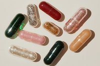 Colorful pharmaceutical capsules and pills scattered on neutral background for medical healthcare supplement design concepts.