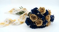 Elegant bridal bouquet with navy blue and gold roses tied with cream ribbon on white background for wedding design and romantic celebrations.