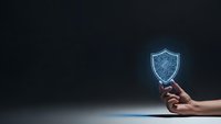 Hand holding glowing digital shield symbol representing cybersecurity protection and data safety on dark background for business presentations.