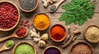 Colorful superfood ingredients and spices arranged on rustic wooden background with goji berries, chia seeds, turmeric, moringa leaves for healthy cooking.