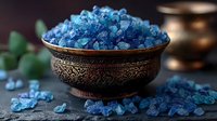 Blue bath salt crystals in vintage copper bowl on dark background, scattered mineral spa aromatherapy salts with soft focus and moody lighting for wellness.