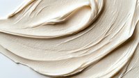 Smooth creamy beige cosmetic texture with elegant swirls and waves creating luxurious skincare product background for beauty industry advertising.