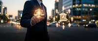 Professional businessman holding glowing justice scales and bank building hologram in urban evening setting representing legal financial services.
