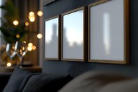 Three empty white frames on dark wall with blurred bokeh lights and cozy sofa in modern living room interior, mockup for artwork or photographs display.